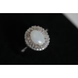 An Oval white opal an diamond cluster ring set in 9ct white gold