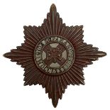 A SCARCE FIRST WAR IRISH GUARDS VOIDED BRONZE PAGRI BADGE, the rayed star with central garter QUIS