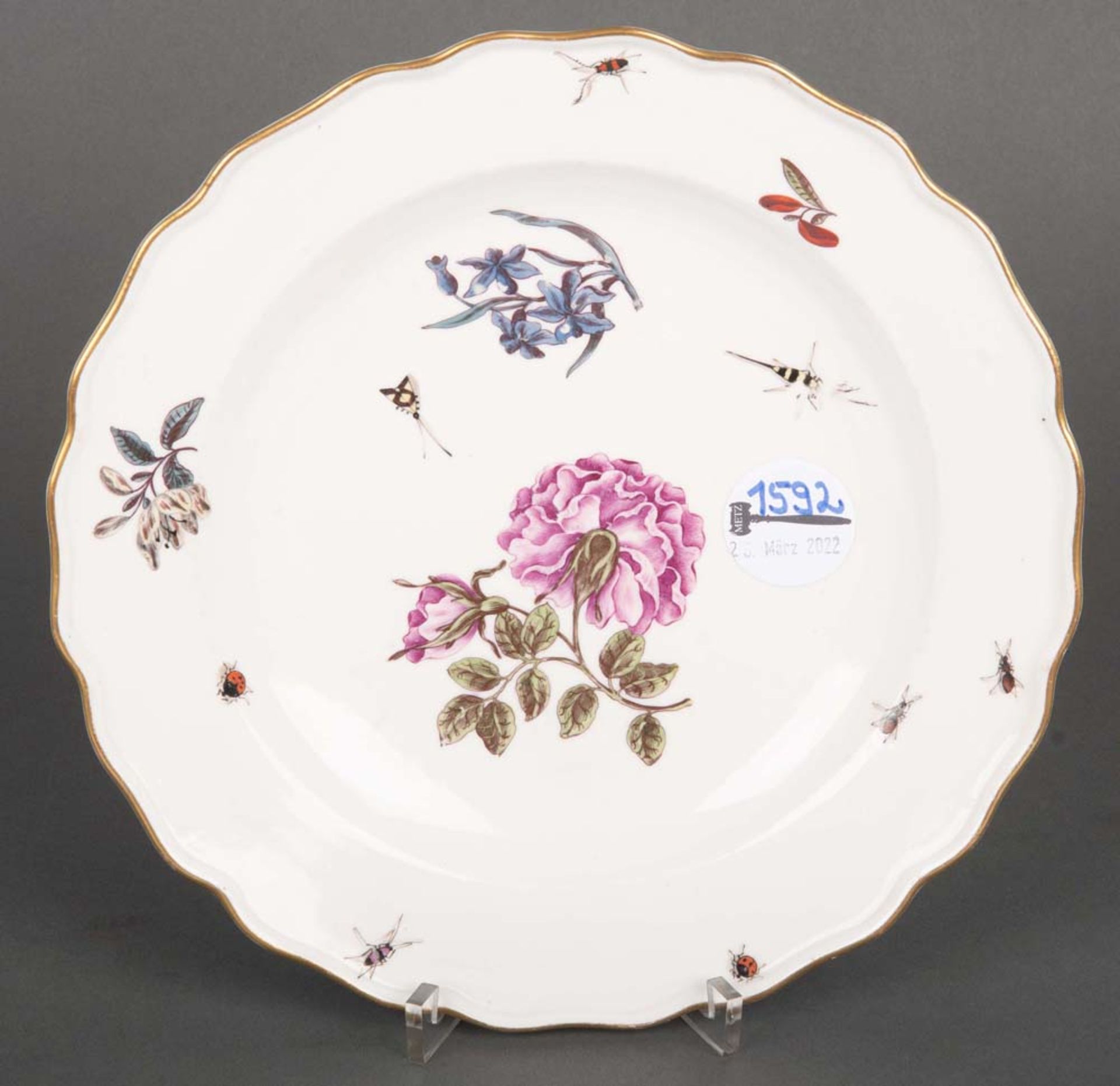 Teller. Meissen 1750. Porzellan, bunt bemalt mit Holzschnittblumen und Insekten, mit Goldrand.