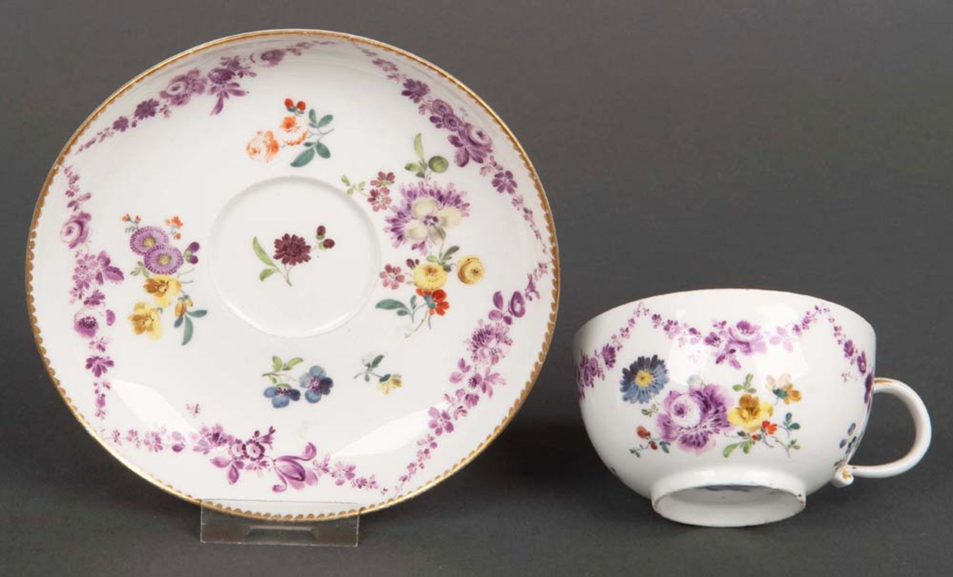 Tasse mit Unterschale. Meissen 1760. Porzellan, purpur und bunt bemalt mit Floraldekor. Am Boden