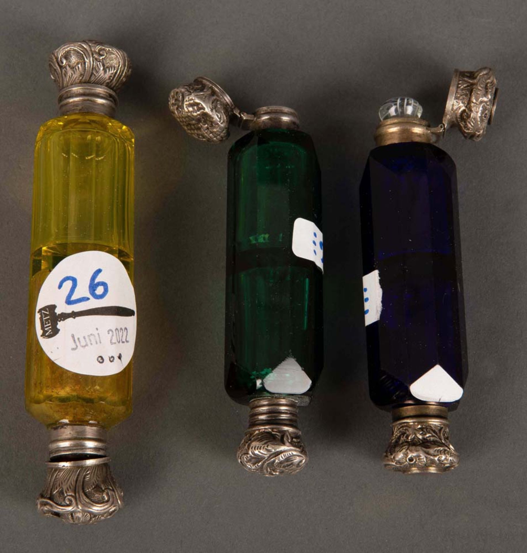 Drei verschiedene Flacons. Böhmen 19. Jh. Farbiges Glas, jeweils mit zwei Silberverschlüssen, H=10