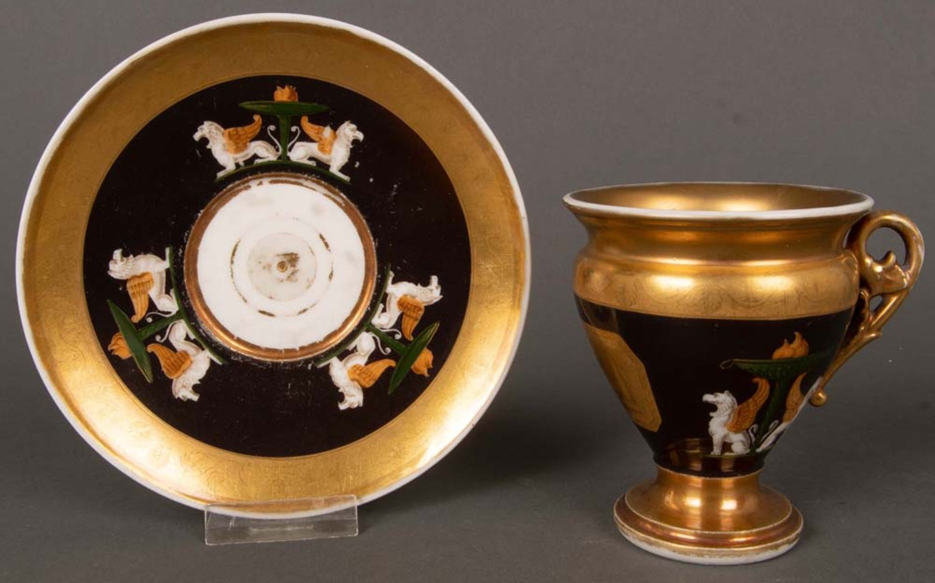 Tasse mit Unterschale. Ludwigsburg 1810. Porzellan, mit dunklem Fond, bunt bemalt mit geflügelten