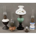 Drei Petroleumlampen, dazu zwei Lampeneinsätze. Deutsch 20. Jh. Glas bzw. Porzellan, Eisengestell,