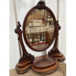 AN OVAL VICTORIAN MAHOGANY SWING FRAME MIRROR ON PLATEAU BASE