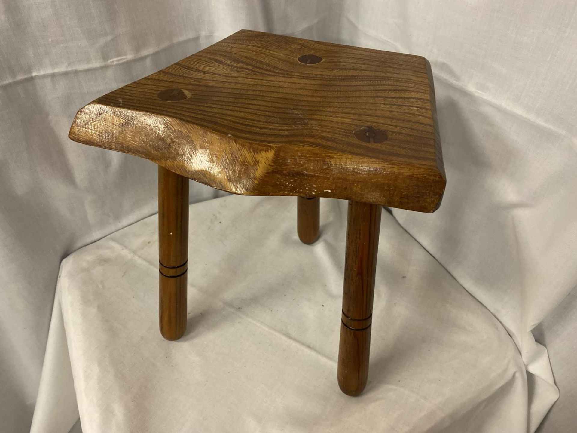 A THREE LEGGED MILKING STOLL WITH OAK TOP AND PINE LEGS