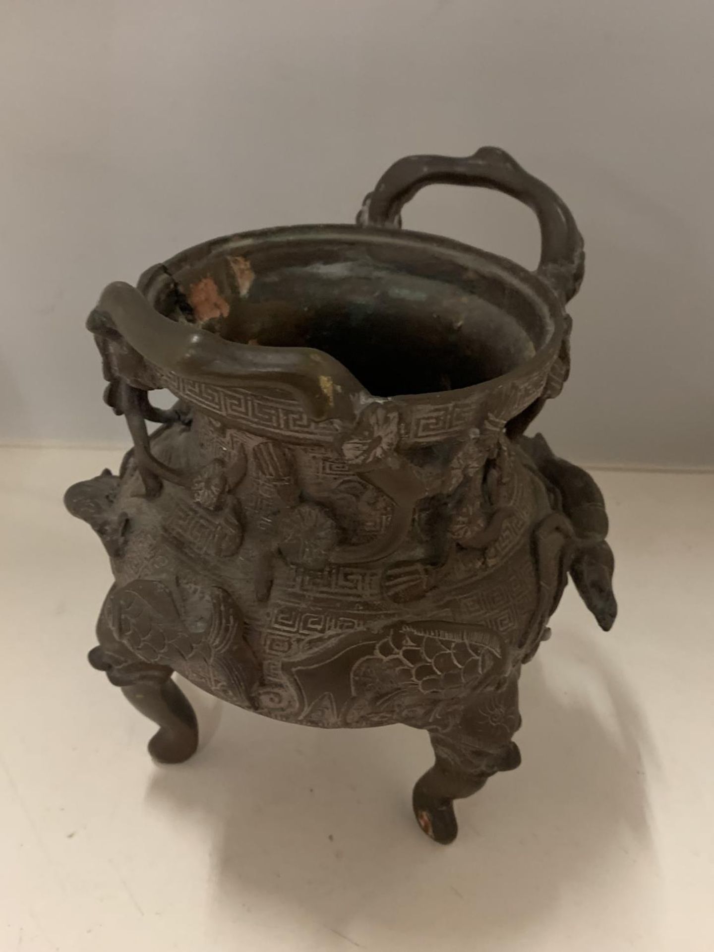 A BRONZE TWIN HANDLED ORIENTAL DESIGNED RINSE CENSOR BOWL DEPICTING FISH AND CHINESE STYLE DRAGON