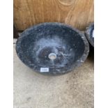 A BLACK WASH BASIN FORMED FROM A SOLID PIECE OF MARBLE