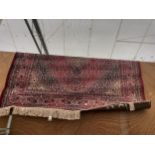 A RED PATTERNED FRINGED CARPET APPROX 76 INCH X 53 INCH
