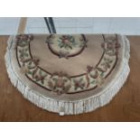 AN OVAL CREAM PATTERNED FRINGED RUG