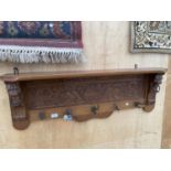 A WOODEN WALL SHELF WITH LOWER COAT HOOK SECTION WITH CARVED LION HEAD DETAIL
