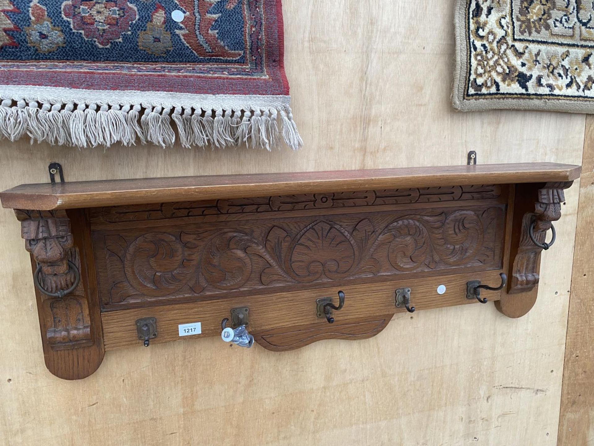 A WOODEN WALL SHELF WITH LOWER COAT HOOK SECTION WITH CARVED LION HEAD DETAIL