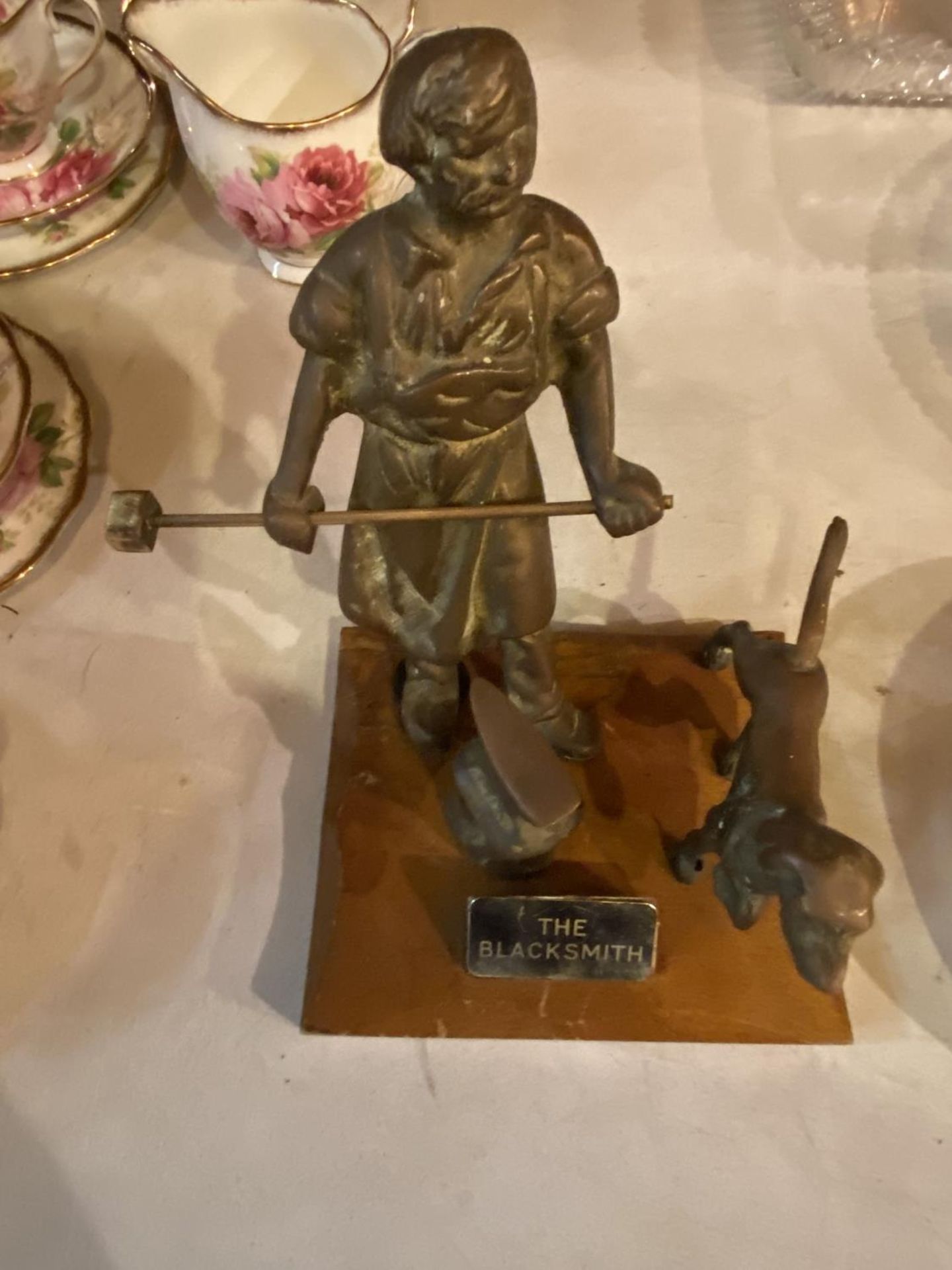 A HEAVY BRASS MODEL OF 'THE BLACKSMITH' MOUNTED ON A WOODEN BASE