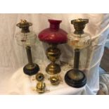 TWO LARGE BRASS OIL LAMPS ON BASES WITH COLUMN STANDS AND A BRASS OIL LAMP CONVERTED TO ELECTRICITY