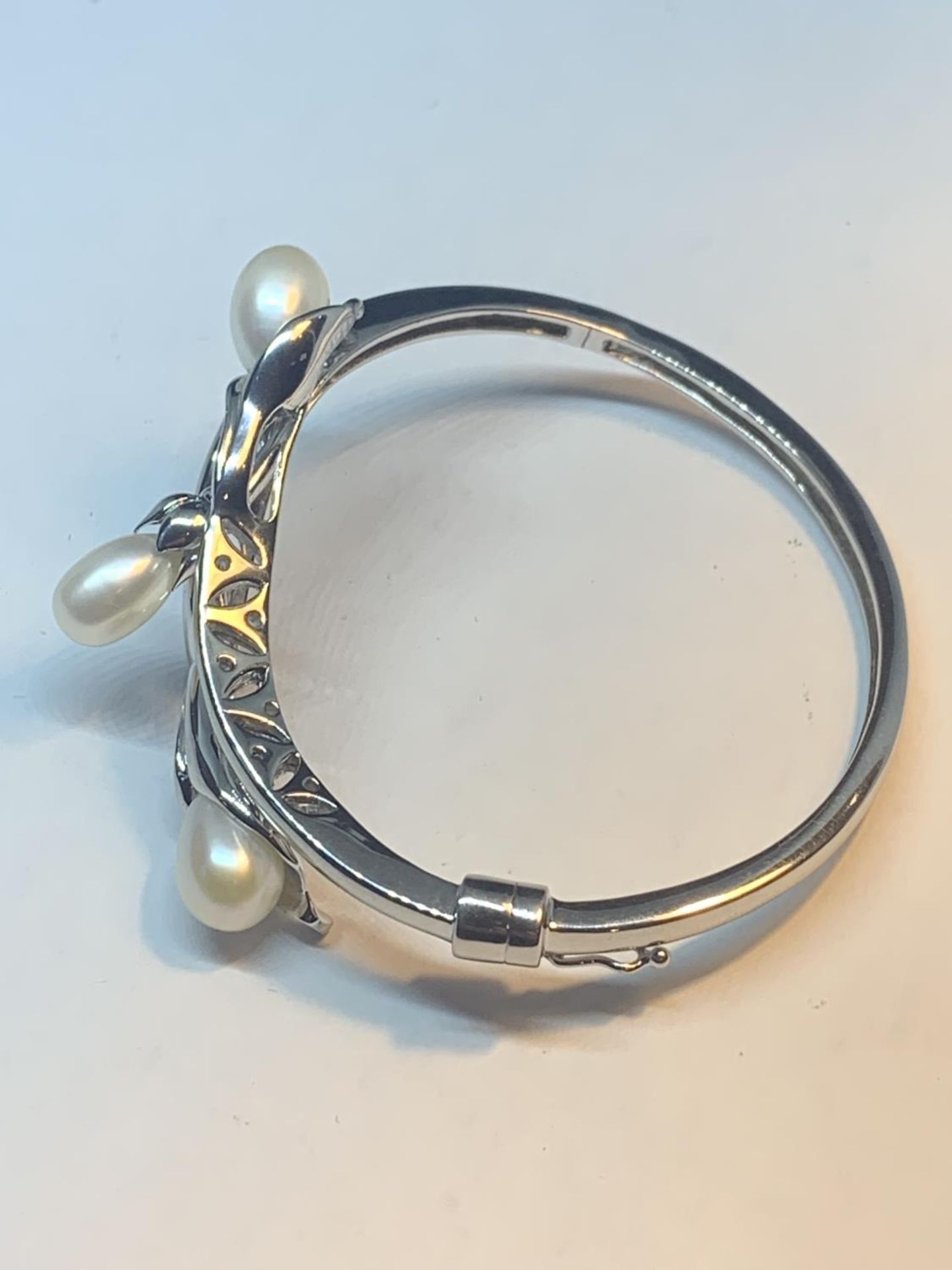 A MARKED 925 SILVER BANGLE WITH THREE PEARLS IN A LILY DESIGN GROSS WEIGHT 23.9 GRAMS WITH A - Image 2 of 5