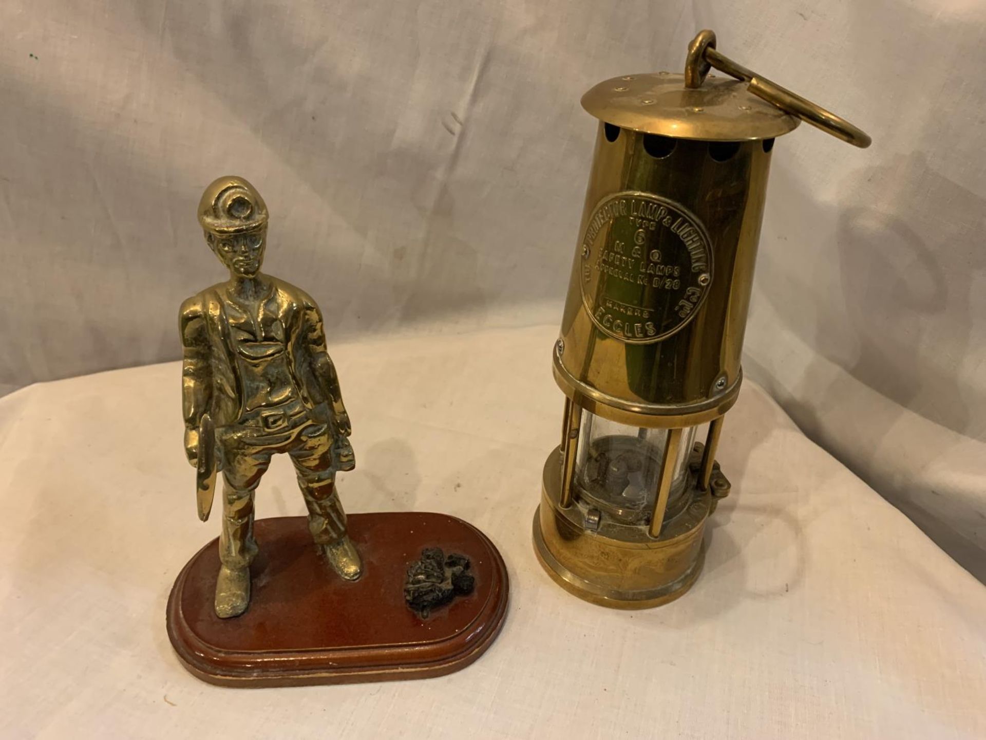 A HEAVY BRASS SAFETY LAMP AND A BRASS MINER WITH COAL ON A PLINTH