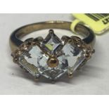 A MARKED 9K GOLD RING WITH PALE BLUE DIAMOND SHAPED STONES AND FIVE CLEAR STONES ON EACH SHOULDER