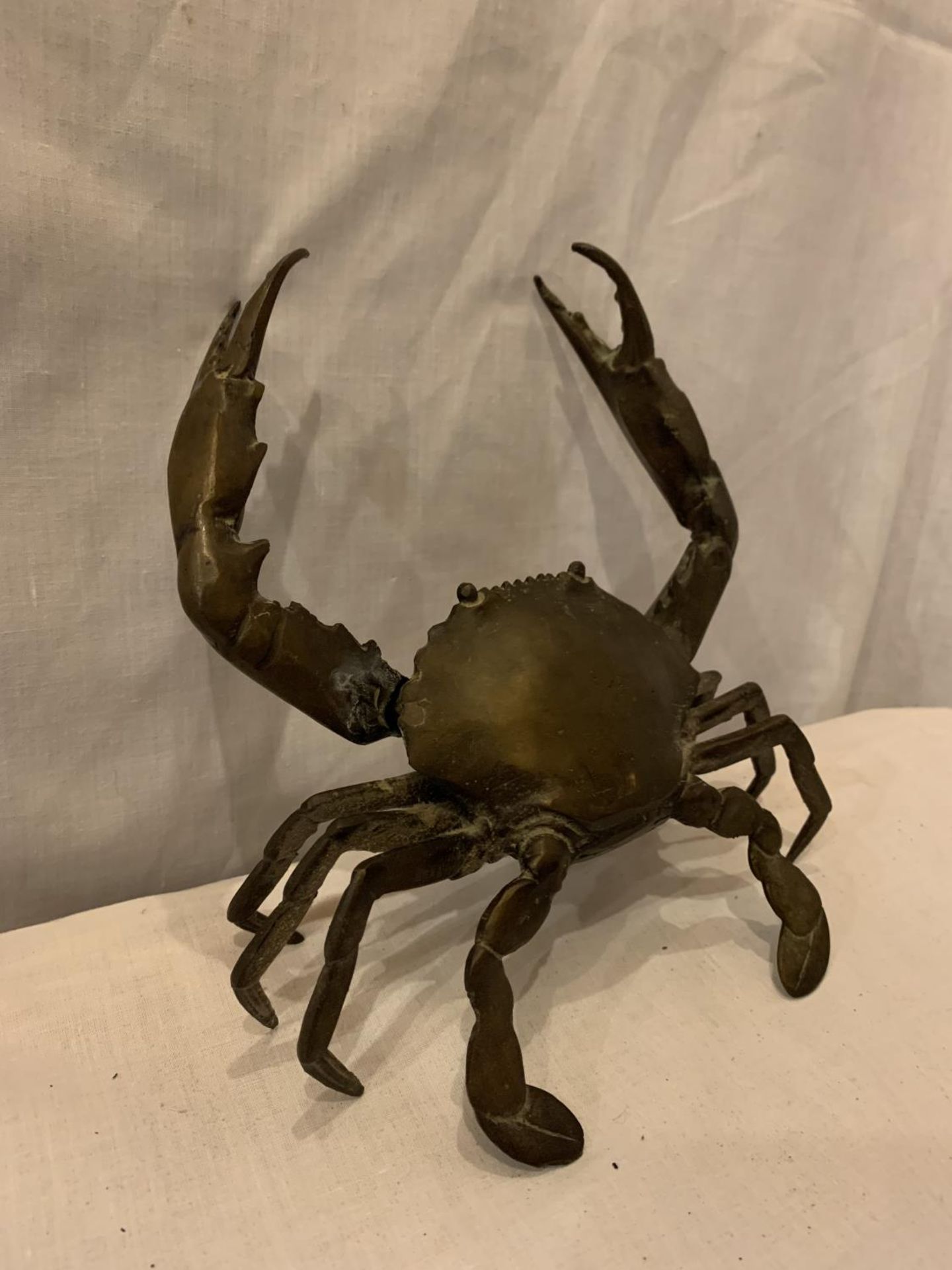 A POSSIBLY BRONZE RAISED CRAB ORNAMENT, ARM A/F