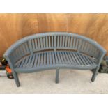 A WOODEN SLATTED CURVED GARDEN BENCH