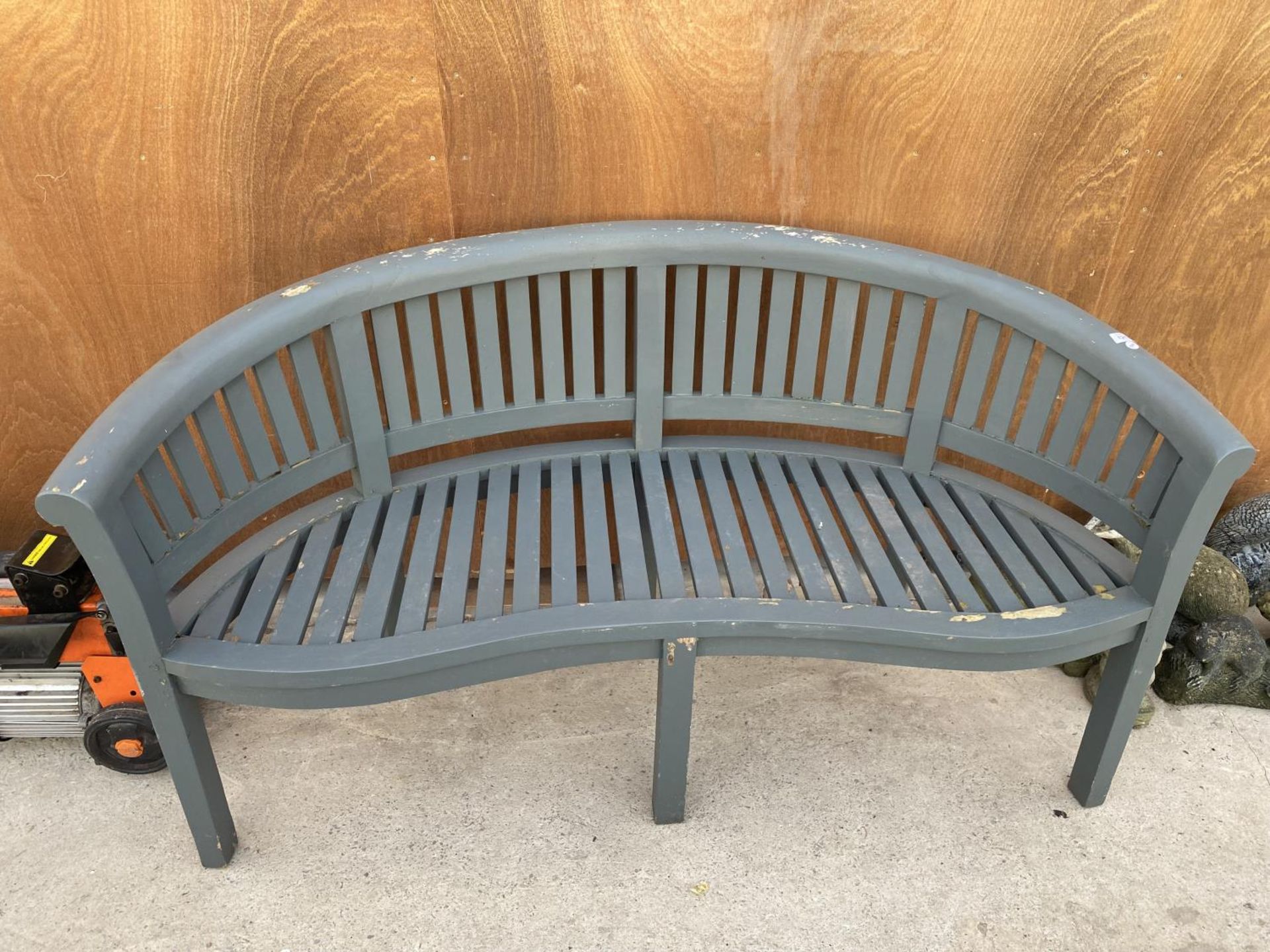 A WOODEN SLATTED CURVED GARDEN BENCH