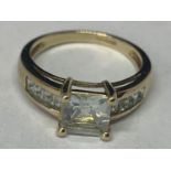 A 9 CARAT GOLD RING MARKED 375 WITH A LARGE CENTRAL SQUARE CLEAR STONE AND FOUR ON EACH SHOULDER