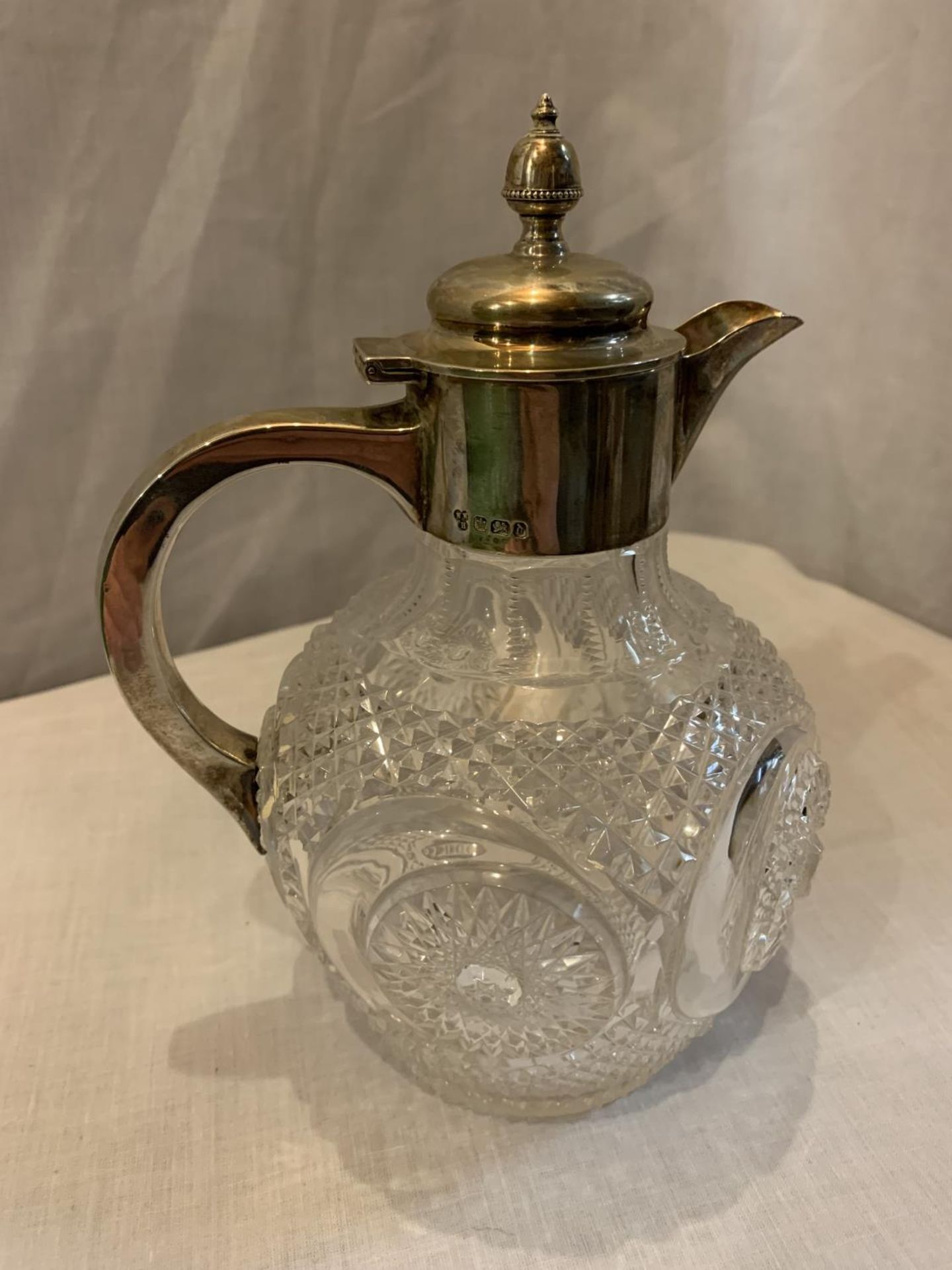 A HEAVY CUT GLASS JUG WITH A HALLMARKED SHEFFIELD SILVER LID AND HANDLE