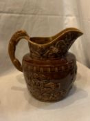 A WOOD LARGE TREACLE GLAZE JUG WITH BEAR AND HUNTING DECORATION AND A HOUND HANDLE