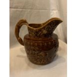 A WOOD LARGE TREACLE GLAZE JUG WITH BEAR AND HUNTING DECORATION AND A HOUND HANDLE