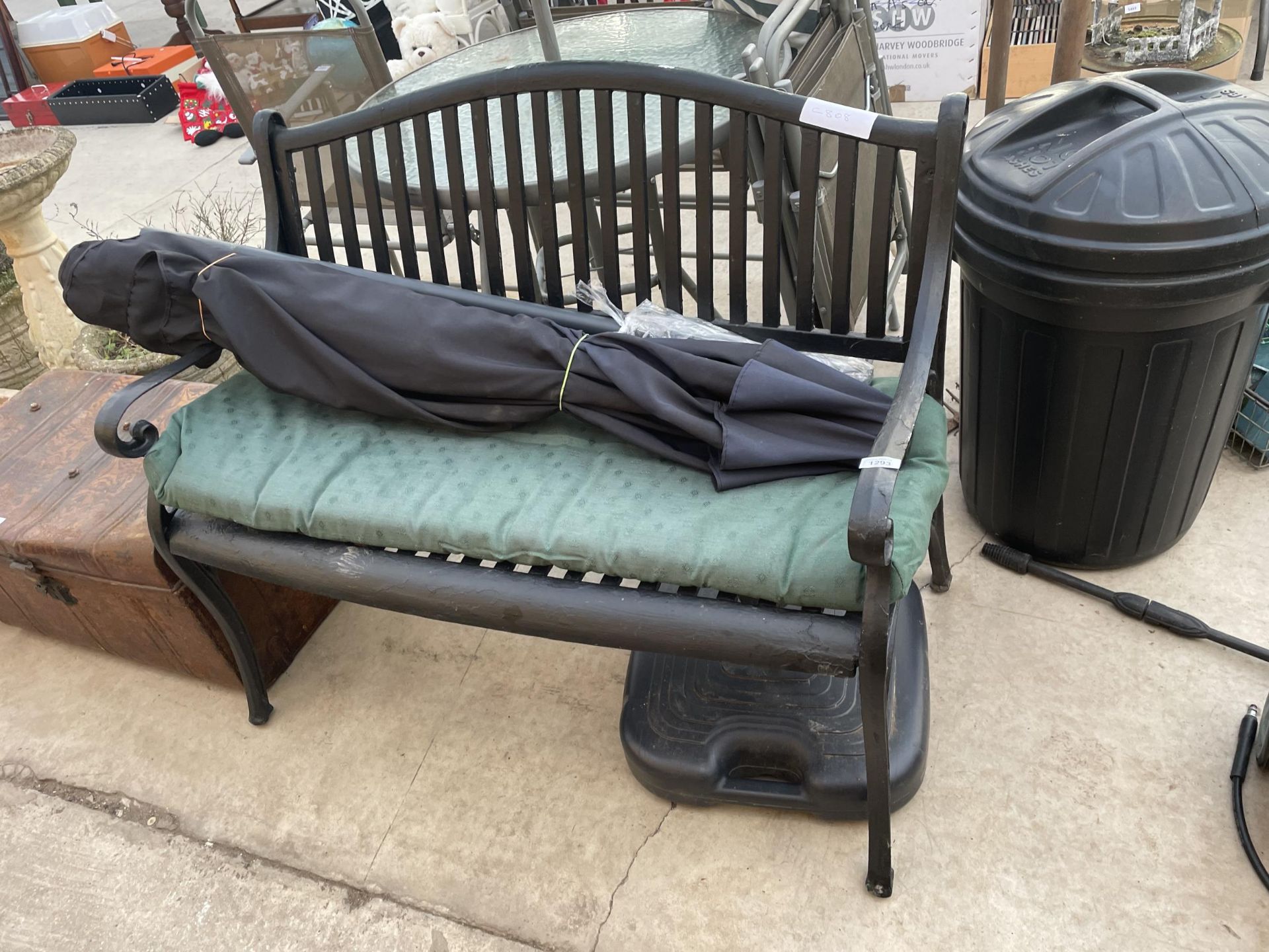 A SLATTED METAL GARDEN BENCH AND A PARASOL