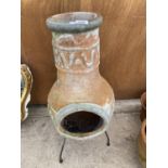 A TERRACOTTA CHIMENEA WITH METAL STAND