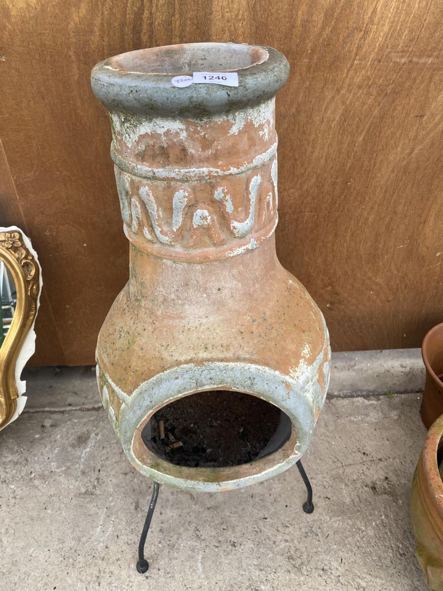 A TERRACOTTA CHIMENEA WITH METAL STAND