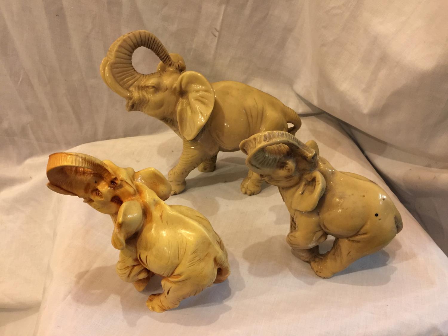 THREE IVORY COLOURED ELEPHANTS HEIGHT 25CM, AND TWO 18CM