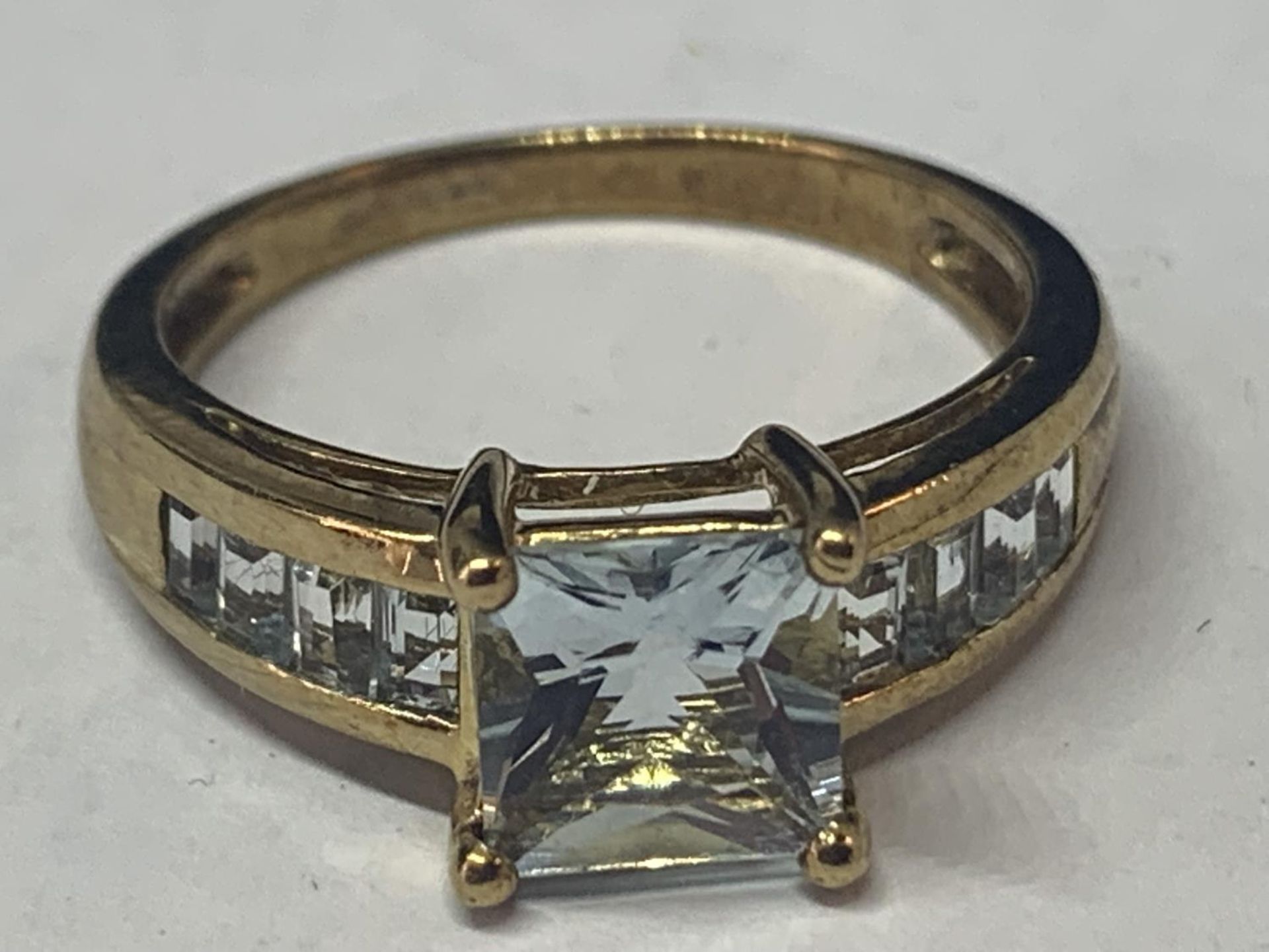 A 9 CARAT GOLD RING MARKED 375 WITH A LARGE CENTRAL PALE BLUE SQUARE STONE AND FOUR MATCHING