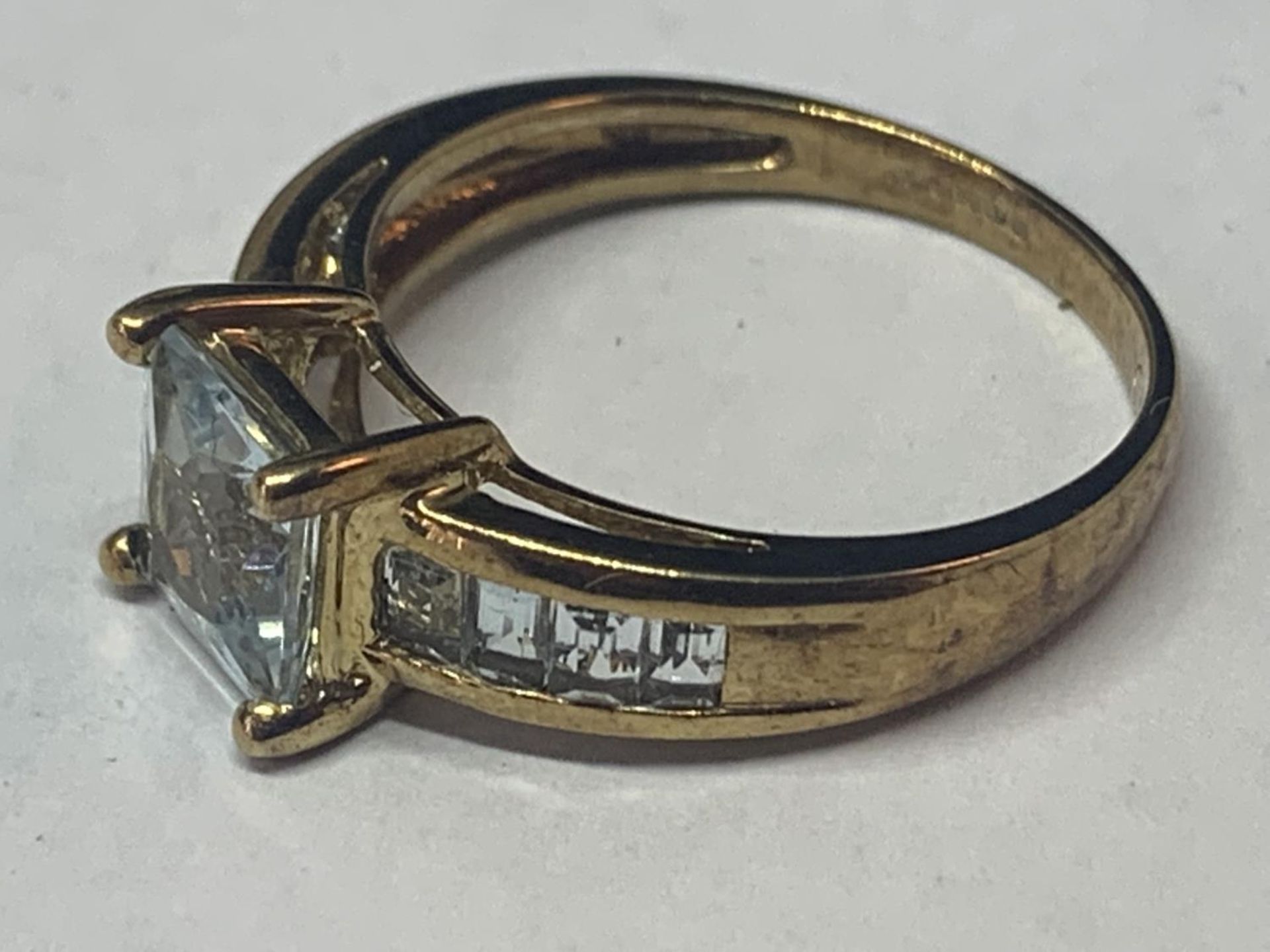 A 9 CARAT GOLD RING MARKED 375 WITH A LARGE CENTRAL PALE BLUE SQUARE STONE AND FOUR MATCHING - Image 2 of 4