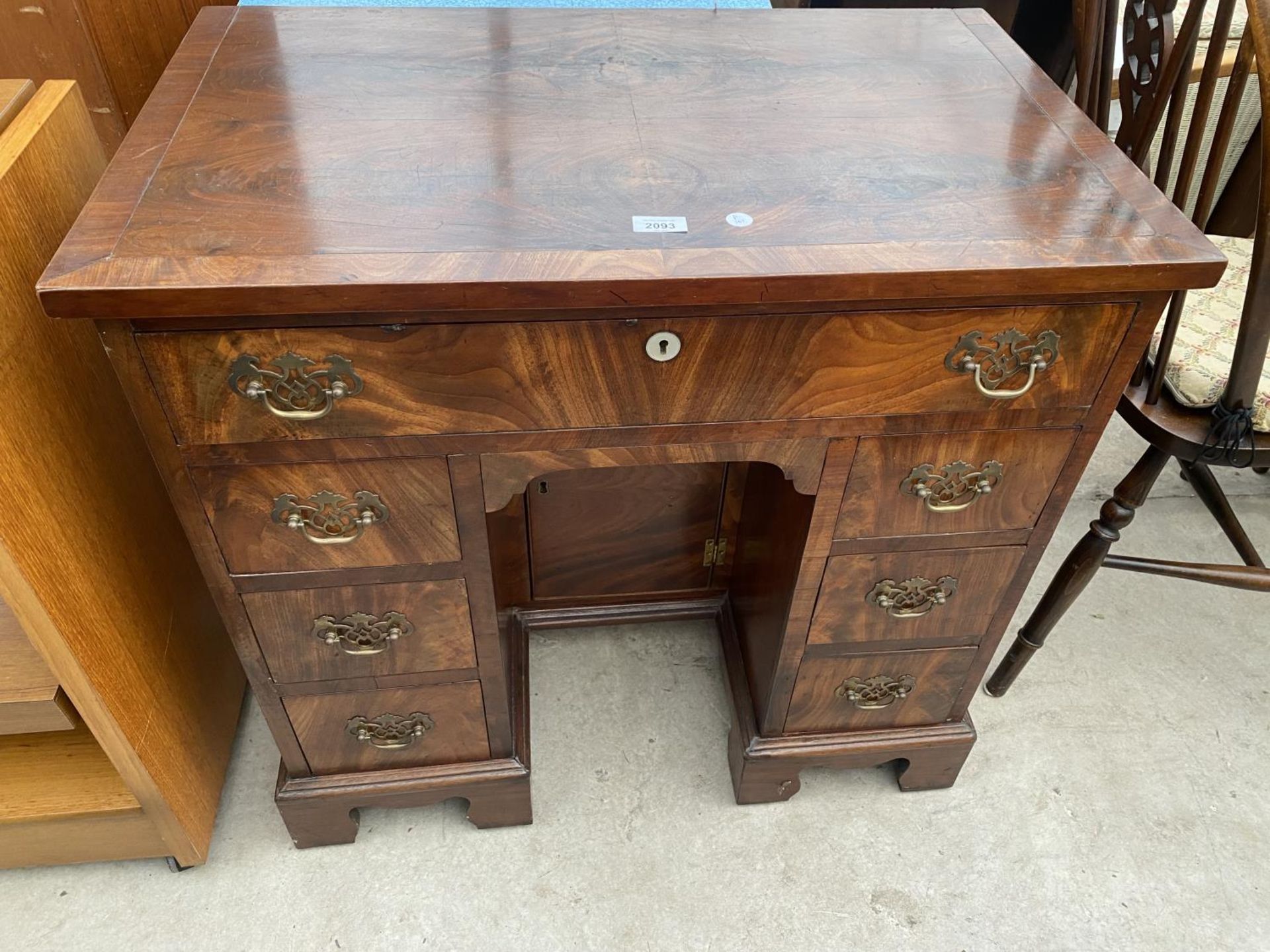 A 19TH CENTURY MAHOGANY AND CROSSBANDED DESK ENCLOSING SEVEN DRAWERS, CENTRAL CUPBOARD ON BRACKET