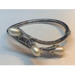 A MARKED 925 SILVER BANGLE WITH THREE PEARLS IN A LILY DESIGN GROSS WEIGHT 23.9 GRAMS WITH A