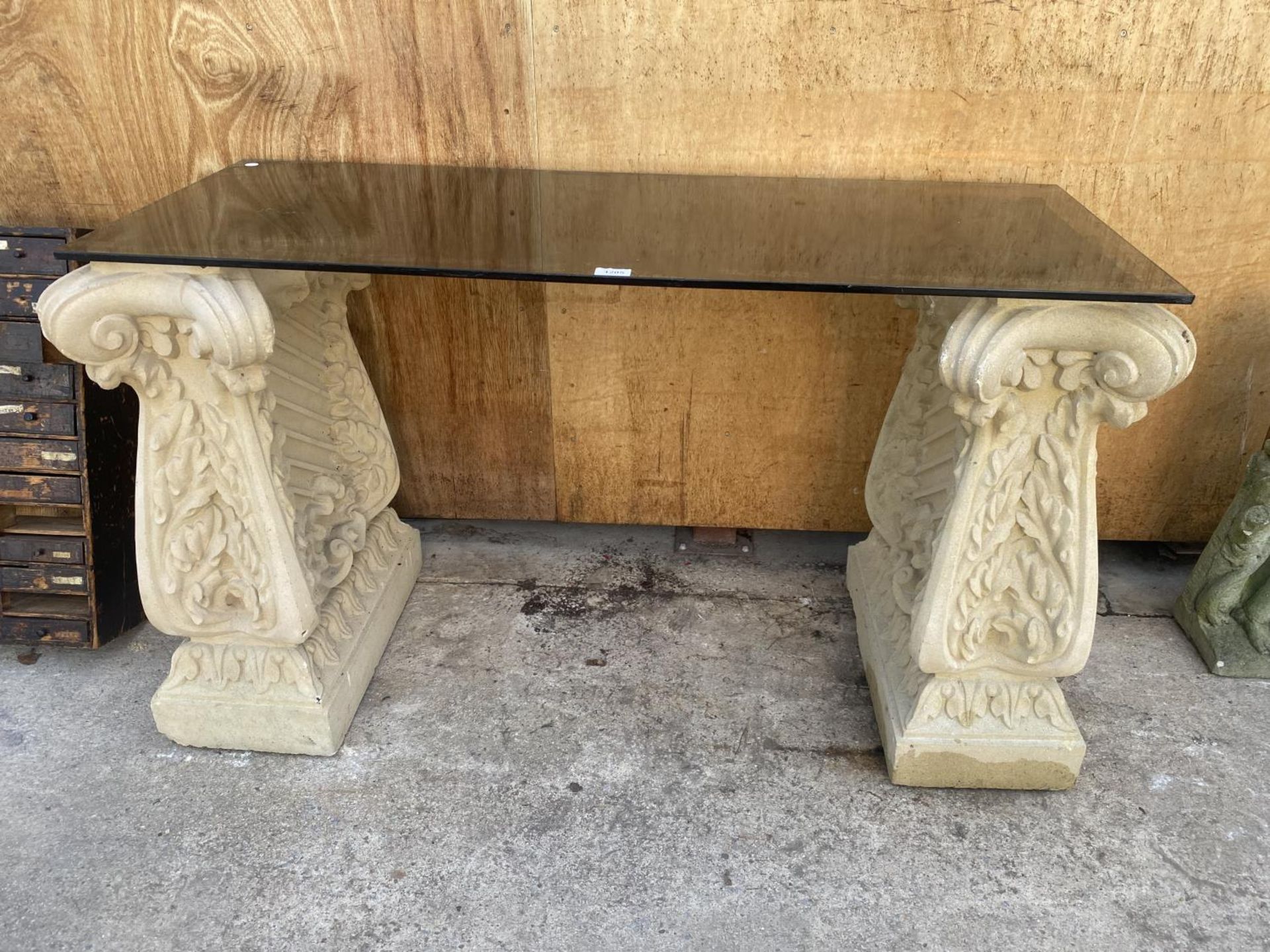 A GLASS TOPPED TABLE WITH RECONSTITUTED STONE PEDASTEL BASES (L:121CM H:73CM)