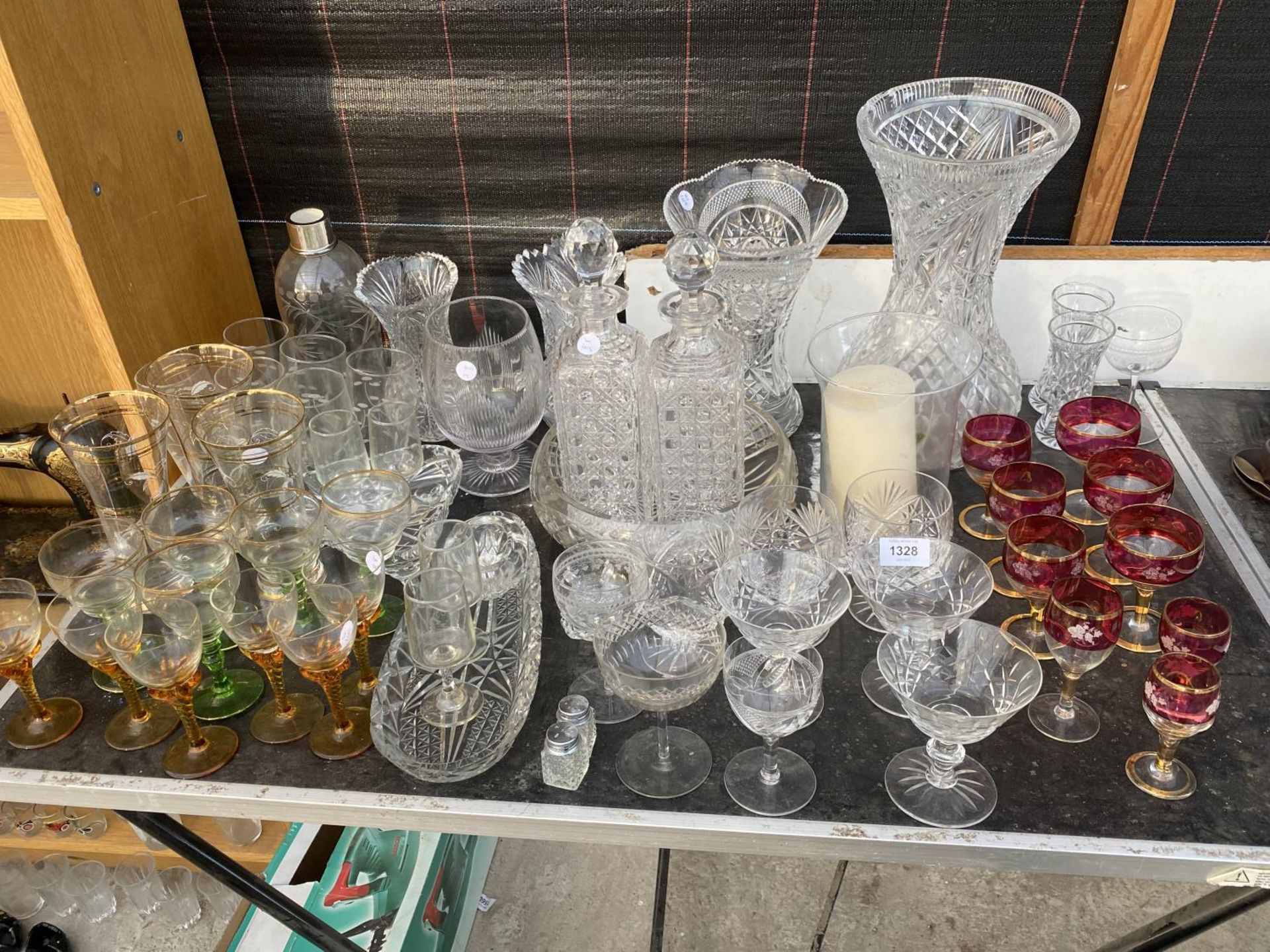A LARGE ASSORTMENT OF GLASS WARE TO INCLUDE DECANTORS, LARGE CUT GLASS VASES AND SHERRY GLASSES ETC