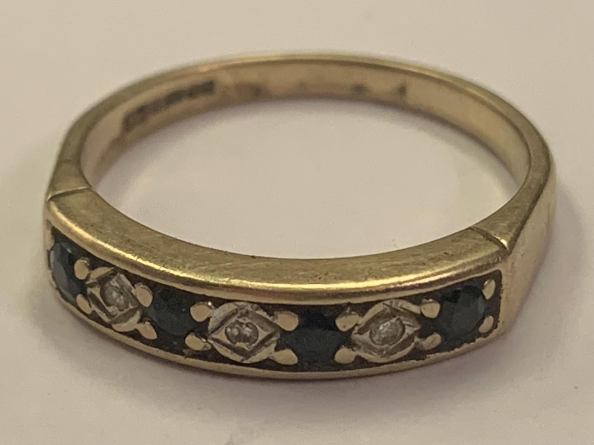 A 9 CARAT GOLD RING WITH FOUR SAPPHIRES AND THREE DIAMONDS IN LINE SIZE O