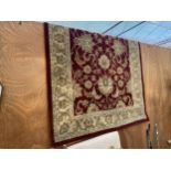 A LARGE RED AND CREAM PATTERNED RUG