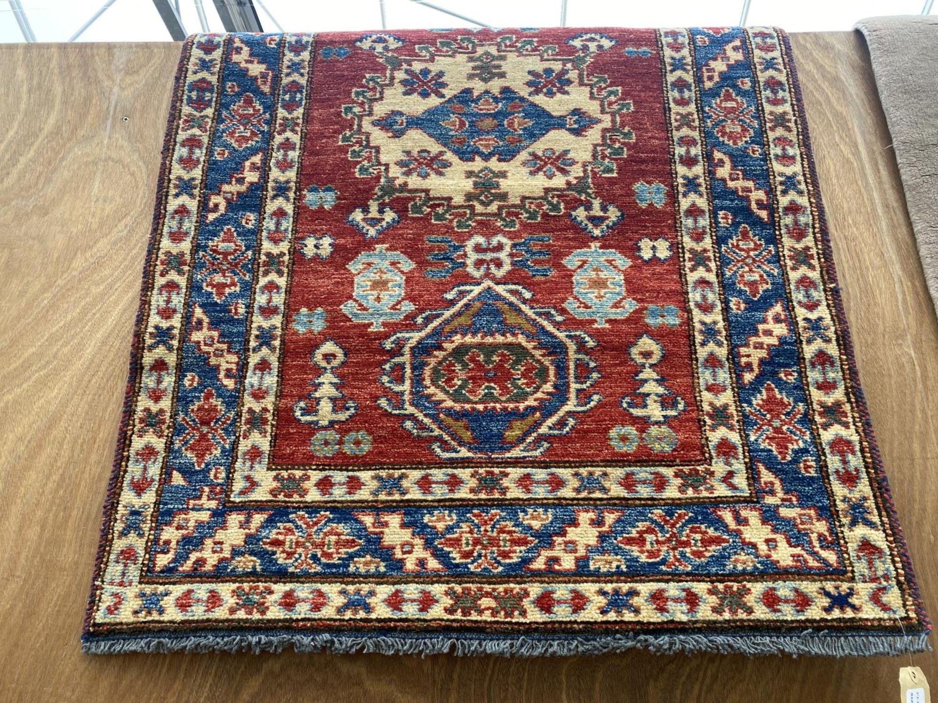 AN AS NEW RED PATTERNED PERSIAN STYLE HANDKNOTTED RUG BEARING THE LABEL OF PERSIAN RUGS DIRECT