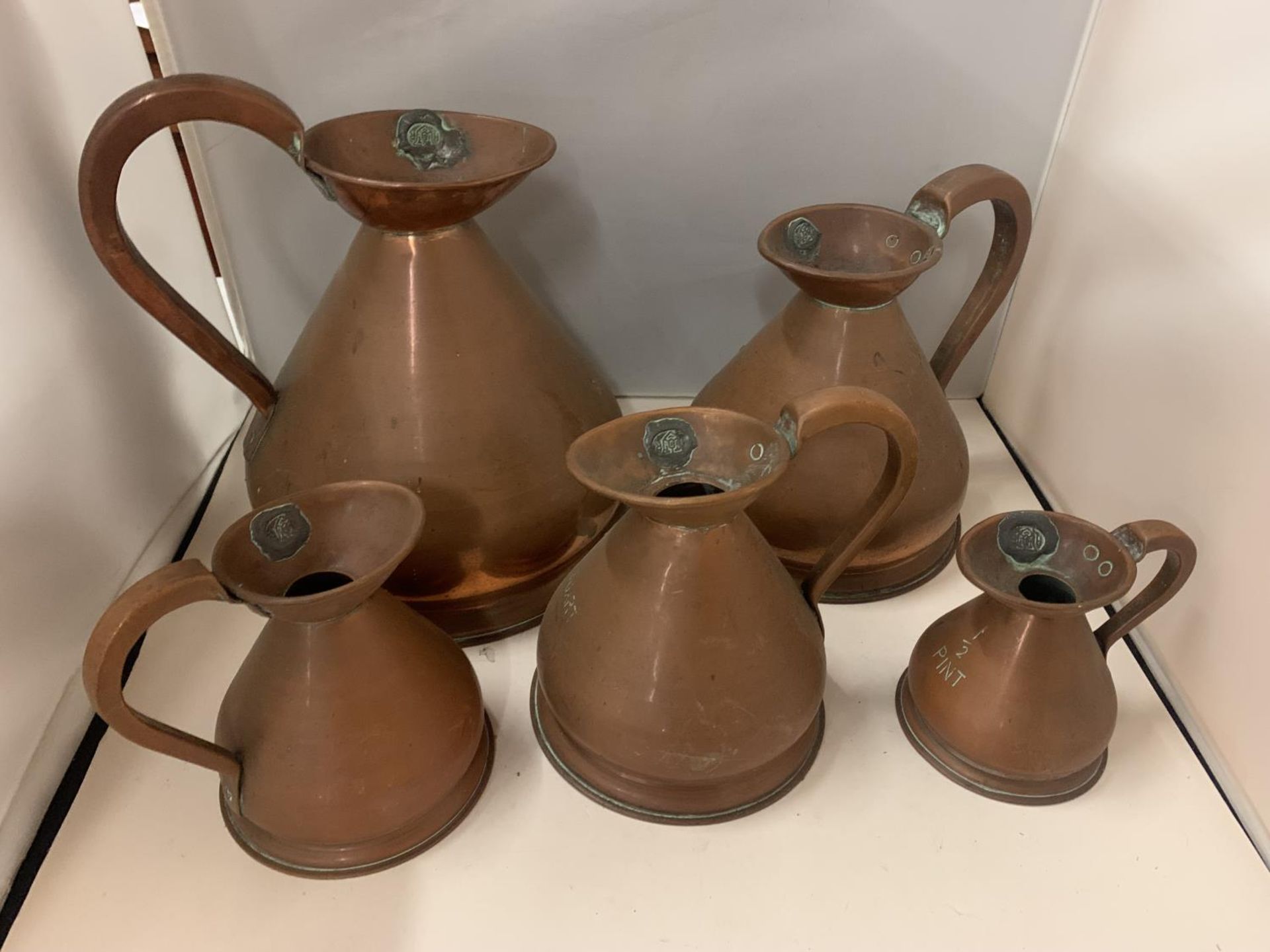 A SET OF FIVE GRADUATED COPPER JUGS MARKED 1/2 PINT TO 1 GALLON WITH SEAL MARKS