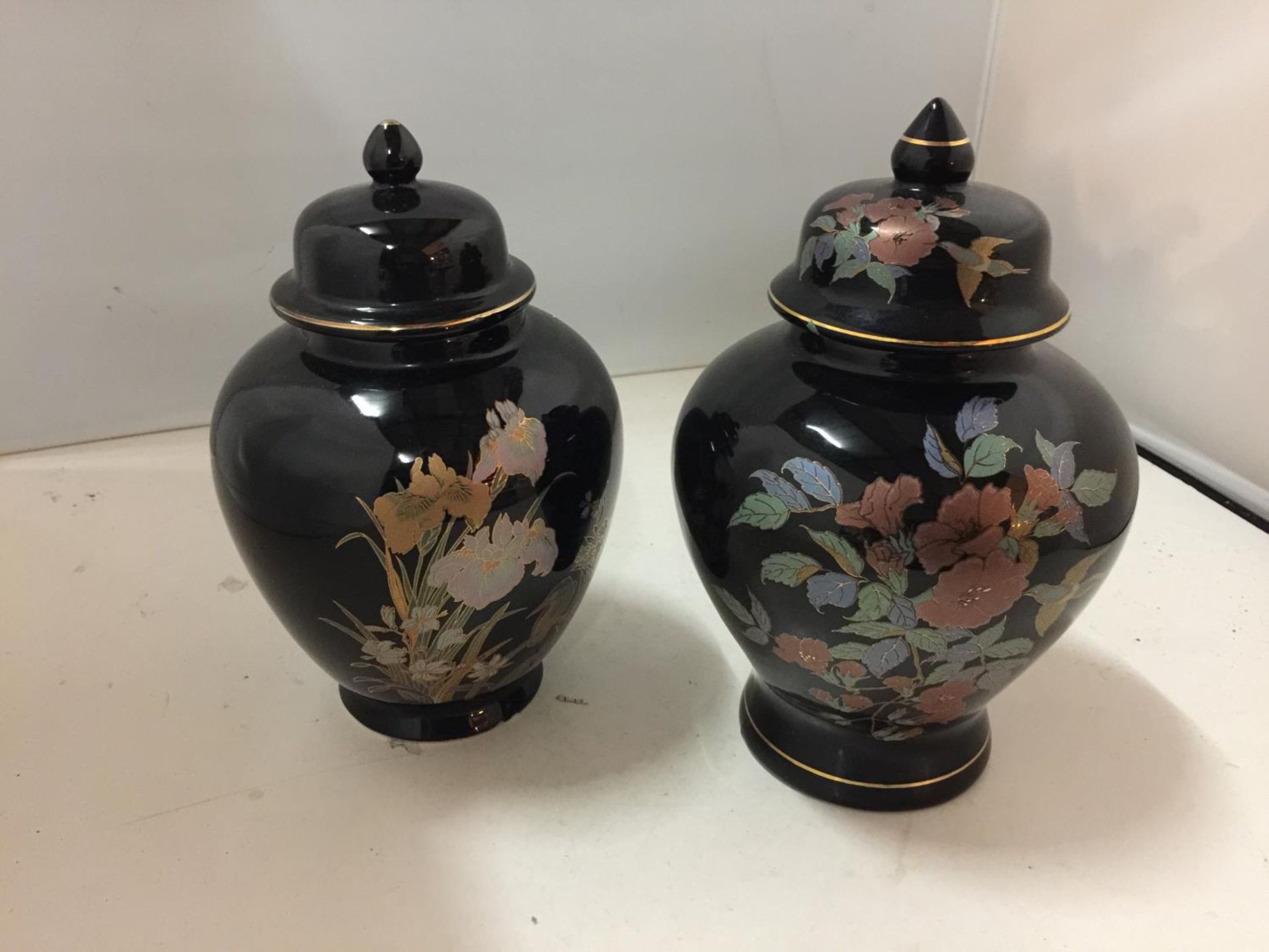 TWO BLACK GLAZED LIDDED STORAGE JARS WITH KINGFISHER AND FLORAL DESIGNS