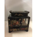AN ORIENTAL STYLE MUSICAL BOX WITH CUPBOARD DOORS OPENING OUT TO DRAWERS WITH ORIENTAL PAINTED