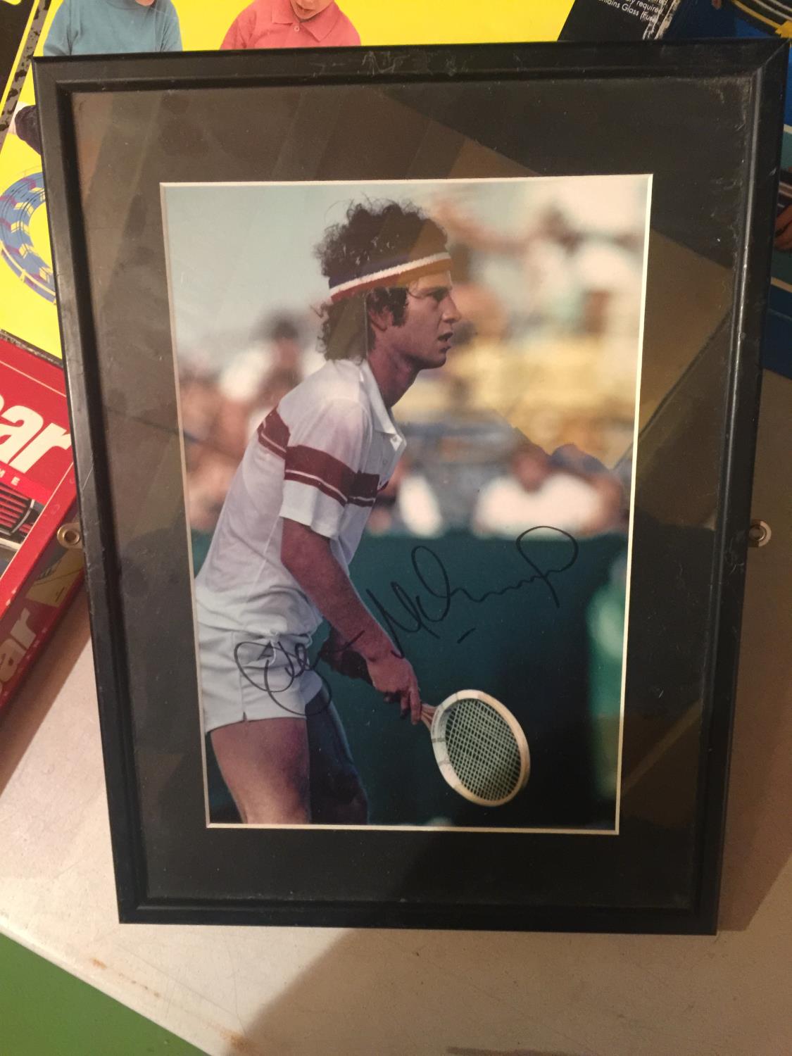 A SIGNED FRAMED JOHN McENROE PHOTO WITH C. O. A.