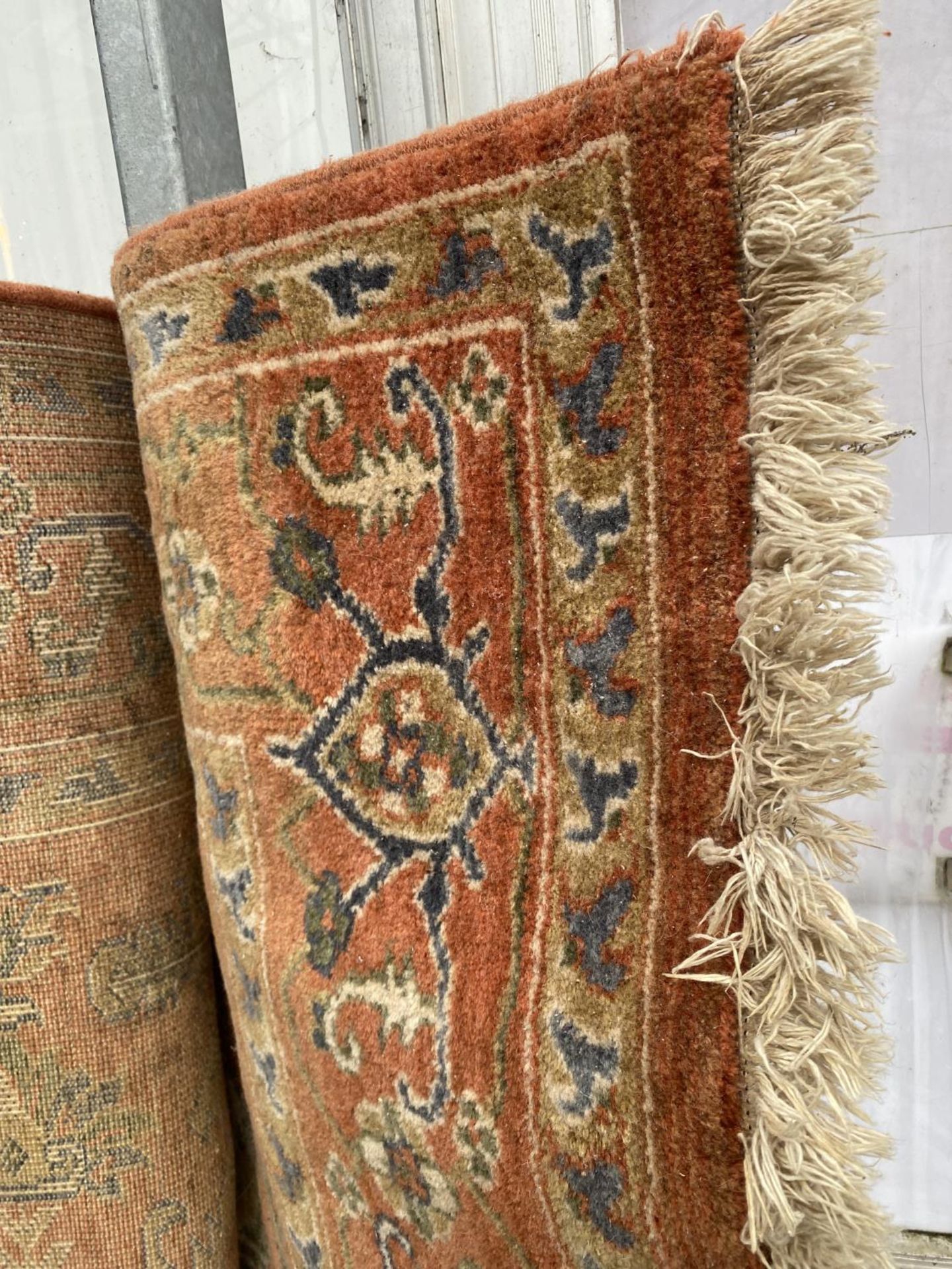 A LARGE ORANGE PATTERNED RUG BEARING A WORN LABEL - Image 2 of 2