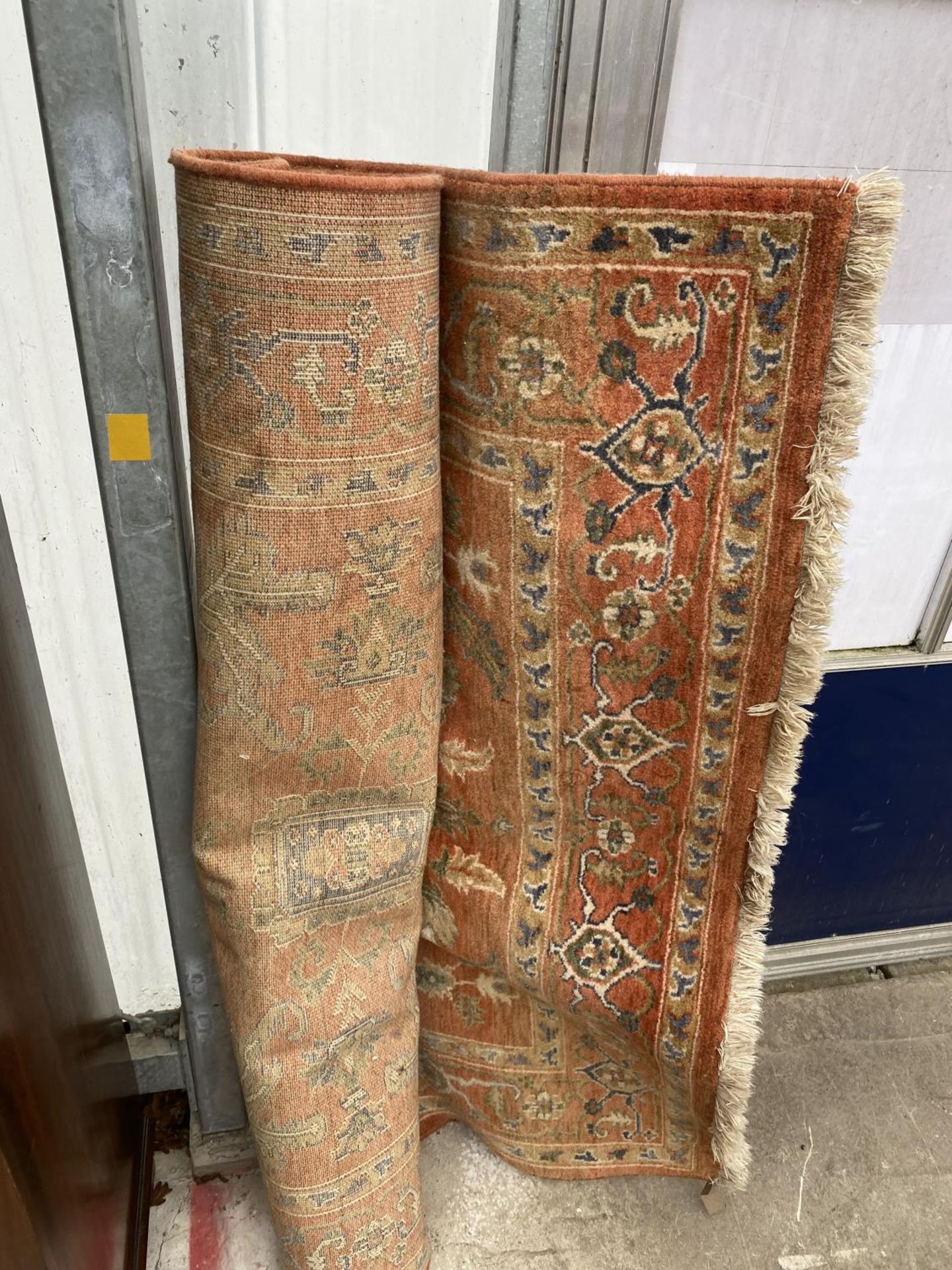 A LARGE ORANGE PATTERNED RUG BEARING A WORN LABEL