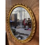 A DECORATIVE OVAL GILT FRAMED WALL MIRROR