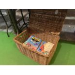 A WICKER BASKET CONTAINING A QUANTITY OF BOOKS TO INCLUDE, DANDY ANNUAL, BLUE PETER ANNUAL,