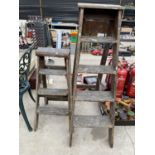 A VINTAGE WOODEN FOUR RUNG STEP LADDER AND A FURTHER THREE RUNG VINTAGE WOODEN STEP LADDER