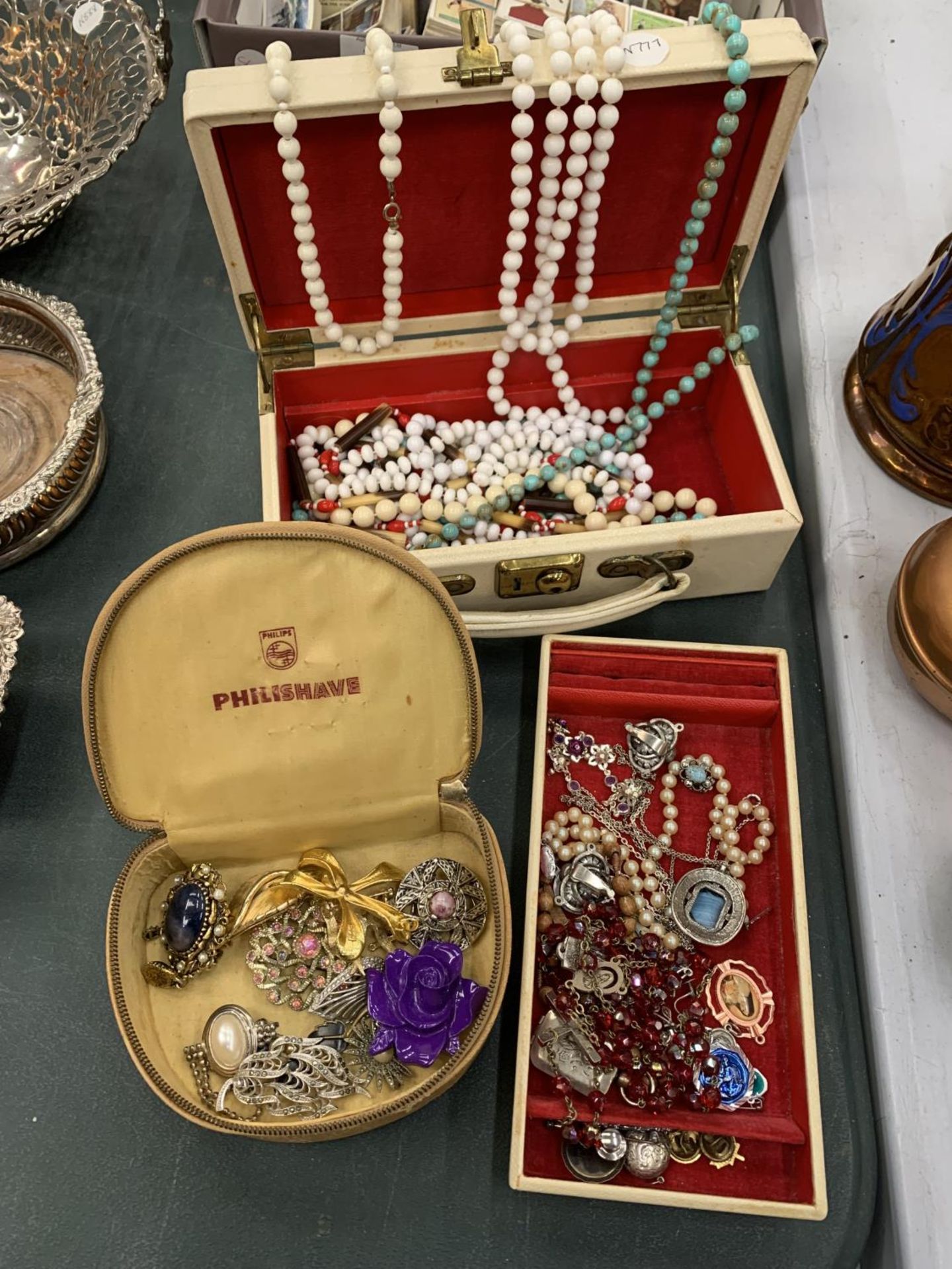 A CREAM JEWELLERY CASE ENCLOSING A NUMBER OF VINTAGE COSTUME JEWELLERY PIECES AND A SECOND CASE OF